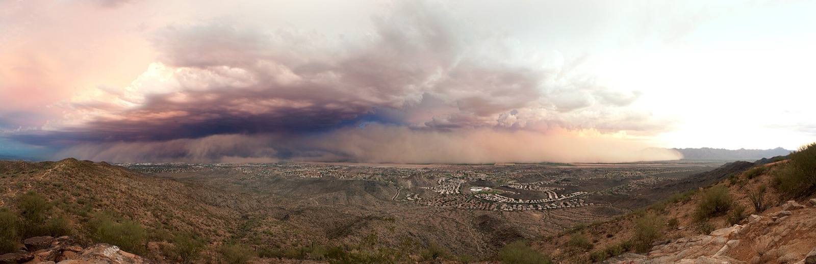 Panoramic view of a massive dust storm front advancing across the Phoenix valley under monsoon thunderclouds