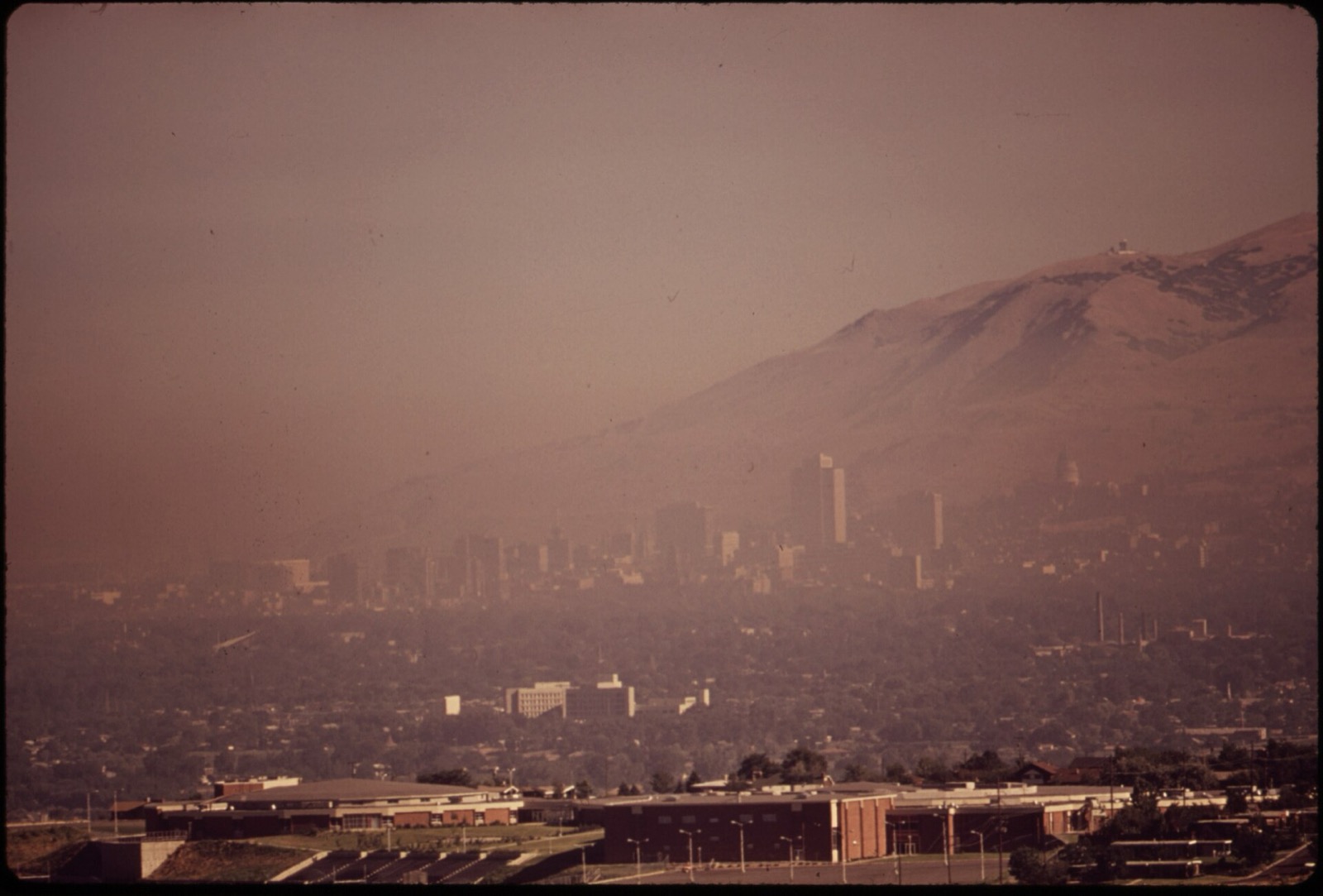 Historic photograph of smog blanketing Salt Lake City, downtown towers barely visible under a haze layer against the mountains
