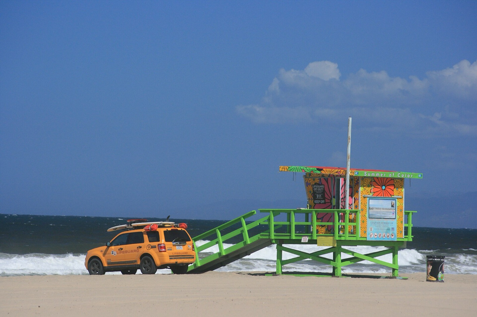 Elevated lifeguard tower on a California sand beach with a lifeguard patrol truck carrying rescue boards parked alongside it