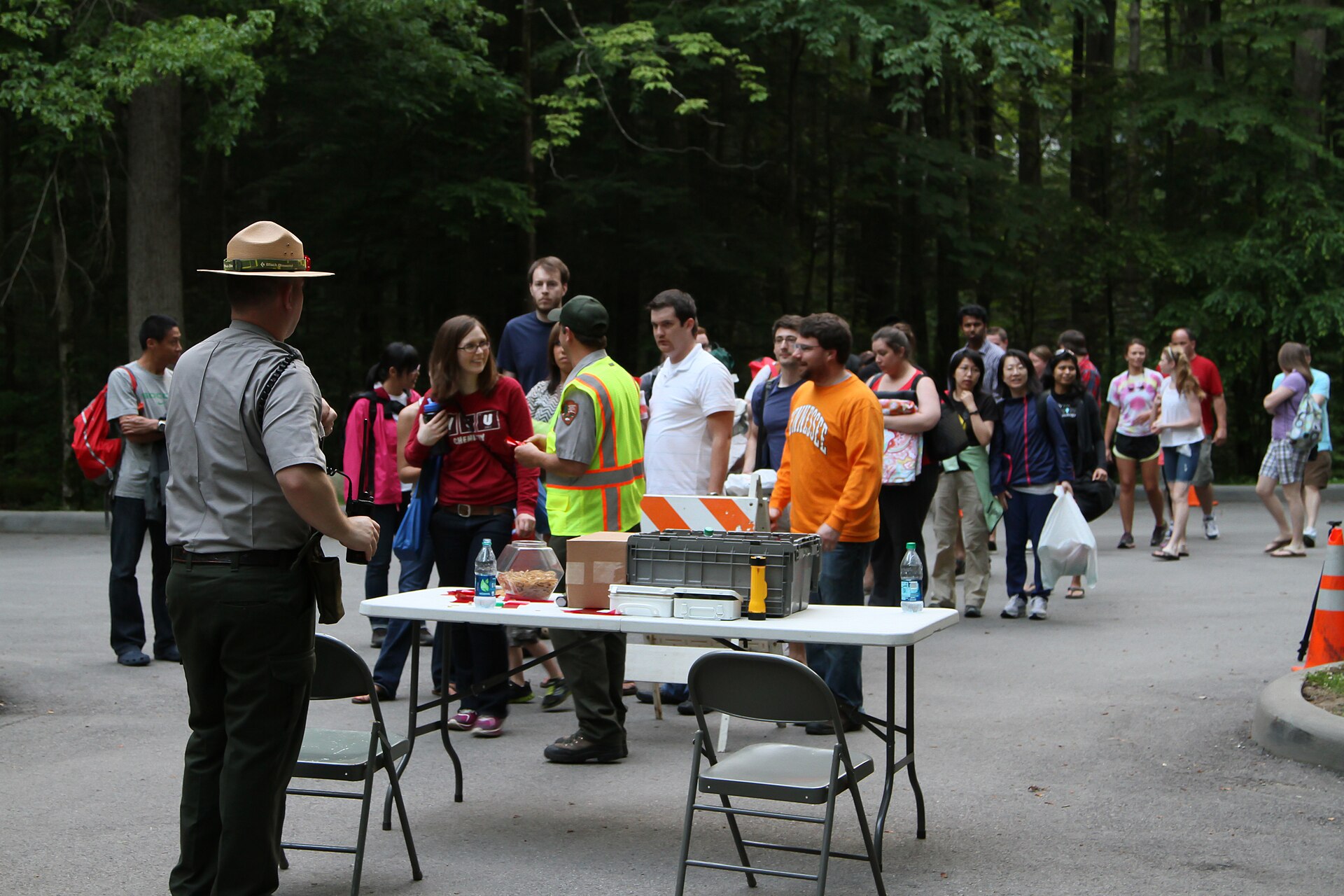 National Park Service rangers checking visitors in at a folding table beside a forest road at the Elkmont firefly viewing event