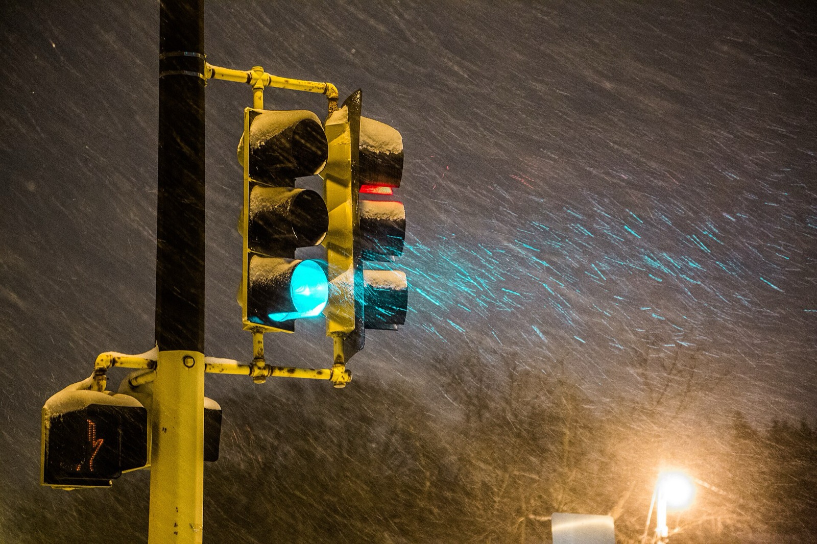 A snow covered traffic signal glowing green through blowing snow at night on Penn Avenue North in Minneapolis