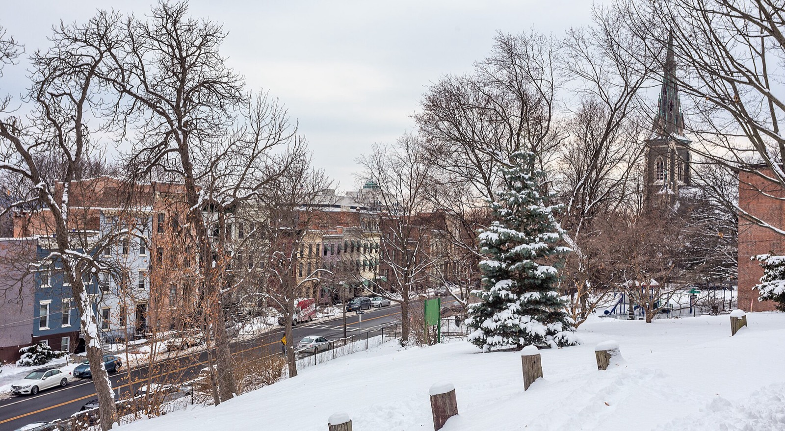 Row houses on a winter street, each with a heating fuel fill pipe at the sidewalk