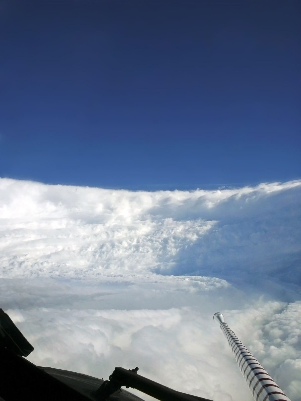 The eye of Hurricane Katrina photographed from inside by a NOAA hurricane hunter aircraft, a stadium of cloud around clear blue sky