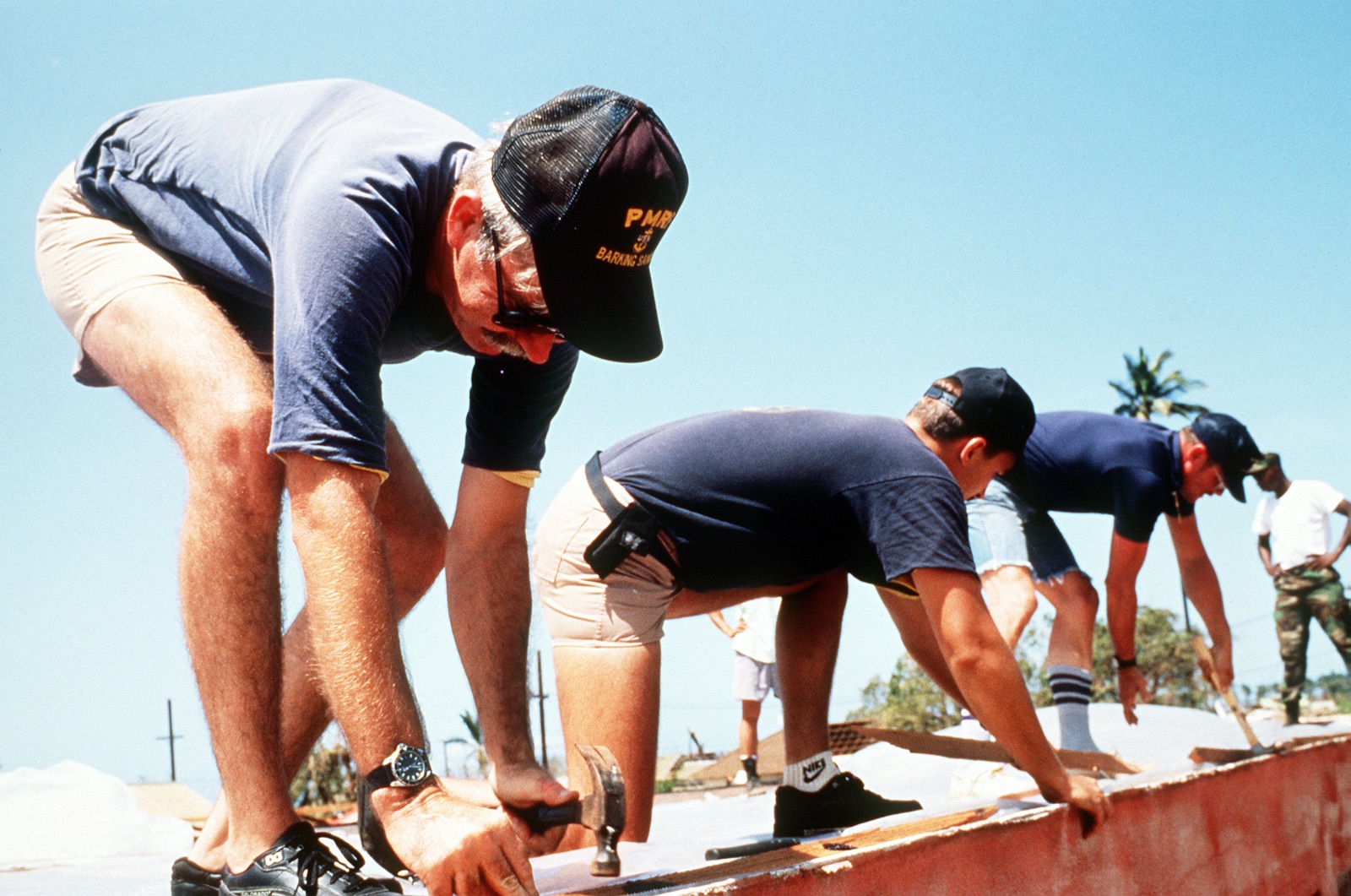 Navy volunteers hammering new roofing onto a building in Waimea, Kauai damaged by Hurricane Iniki