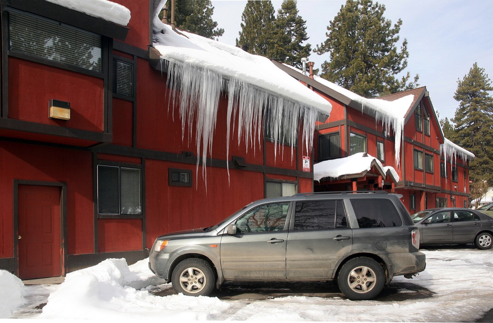 A heavy slab of snow overhanging a lodge eave at South Lake Tahoe with a row of long icicles