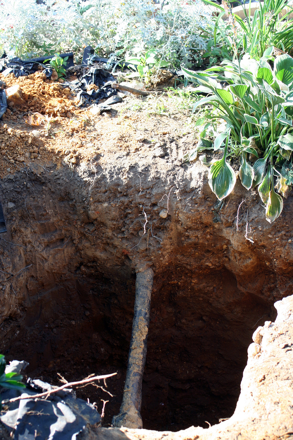 A water service line exposed in an excavation, the pipe running from the main to a building