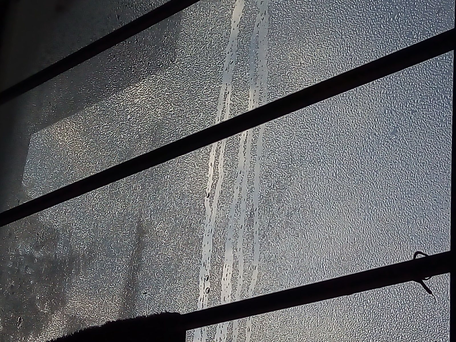 Heavy condensation running down the inside of a window pane, with clear tracks where water has drained through the fogged surface