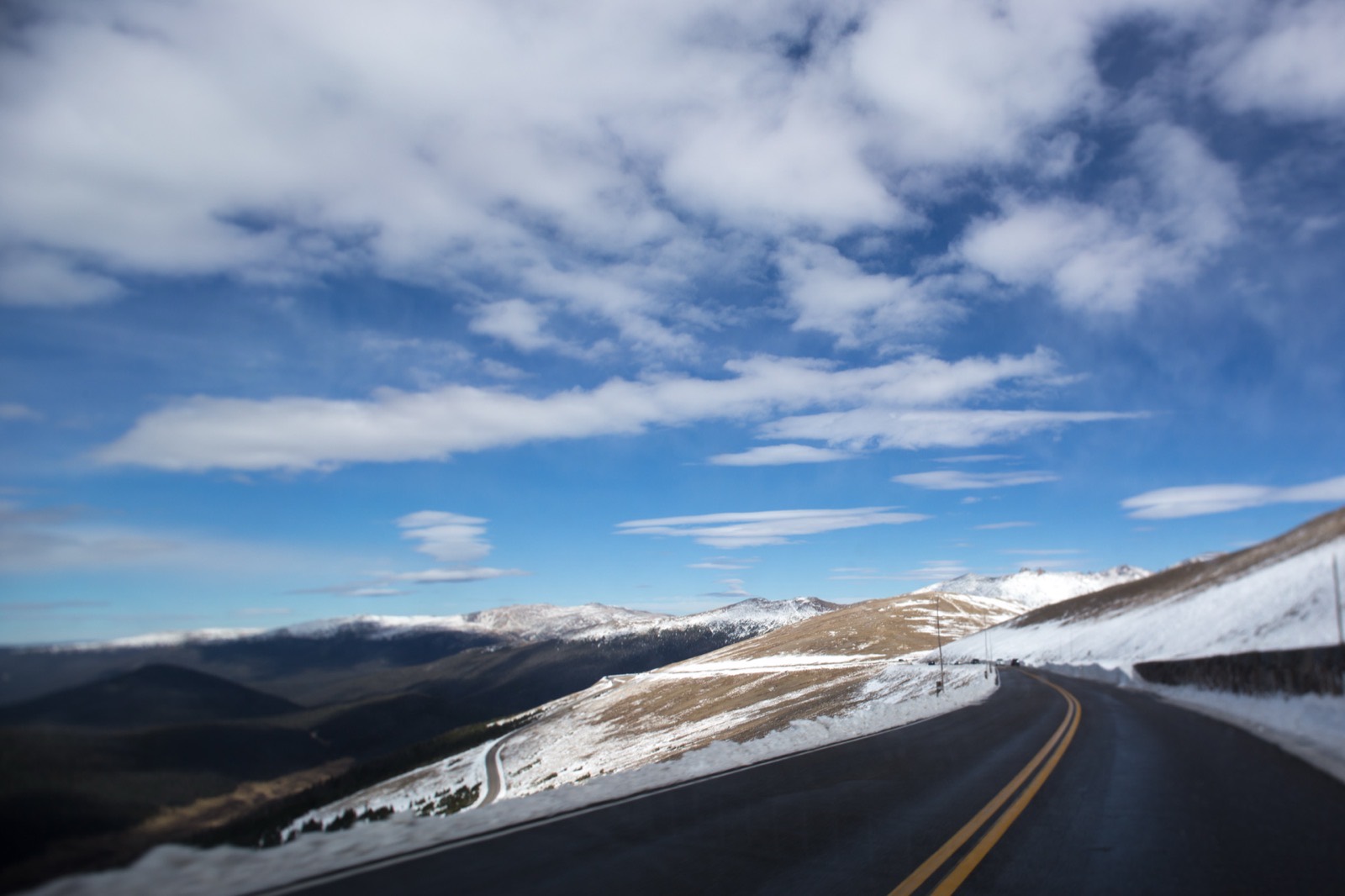 Trail Ridge Road curving across open tundra above treeline in Rocky Mountain National Park with snow banked along the shoulder