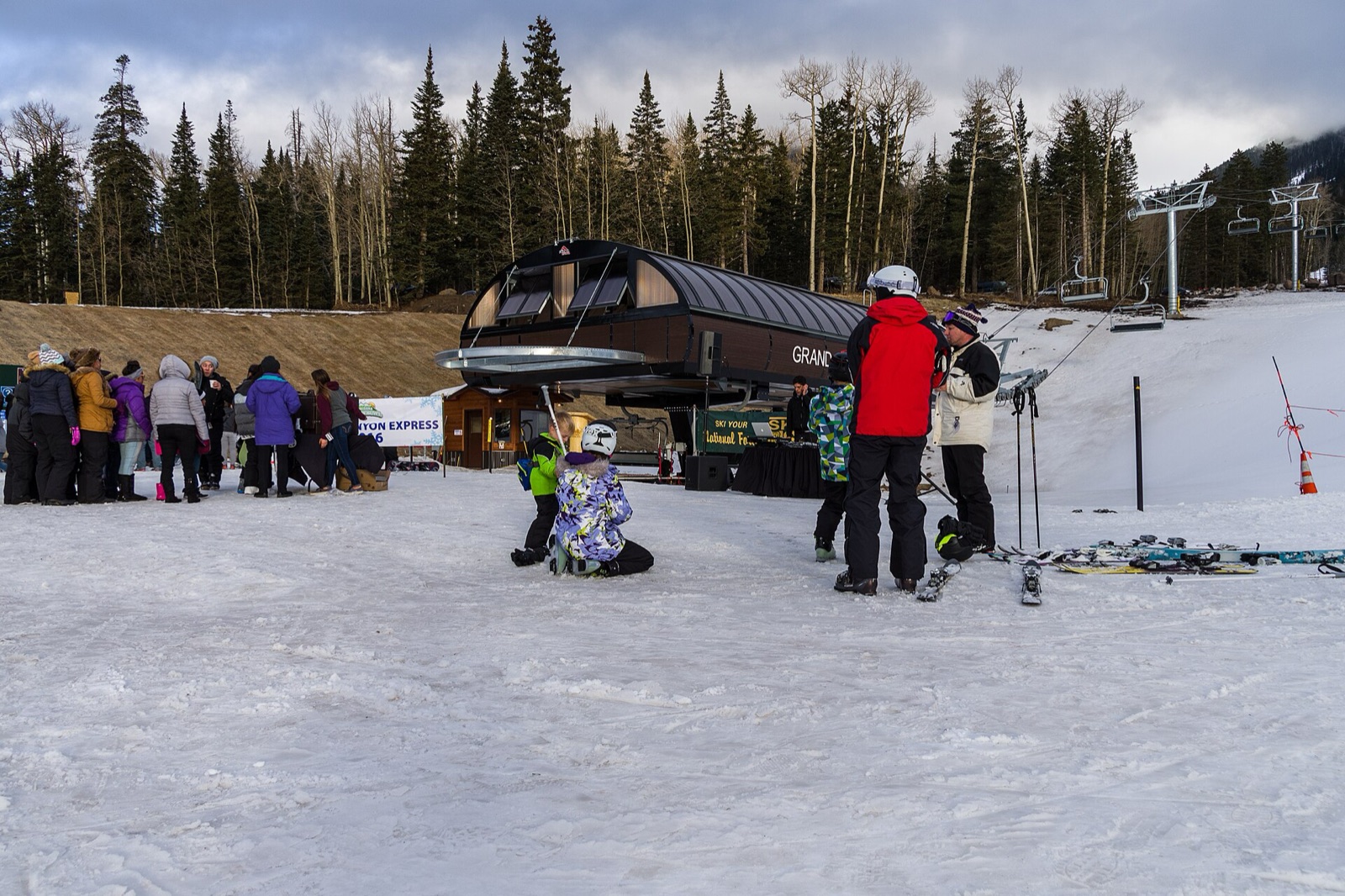 Skiers and families gathered at the base of a chairlift at Arizona Snowbowl