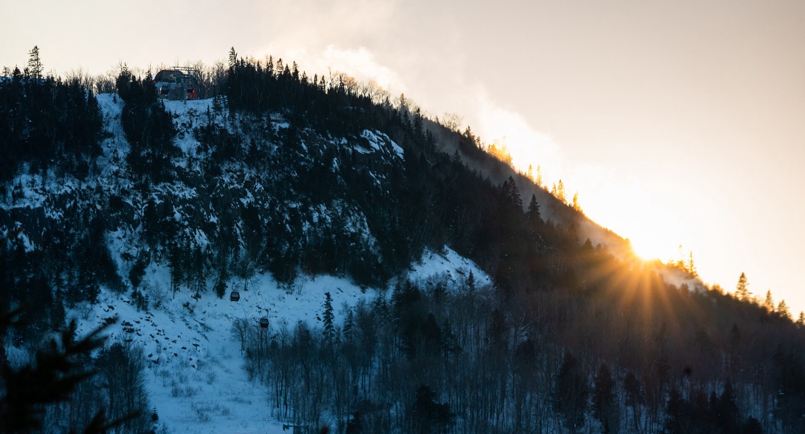 Sun setting behind a snow-covered ski hill and gondola line at Lutsen Mountains in Minnesota