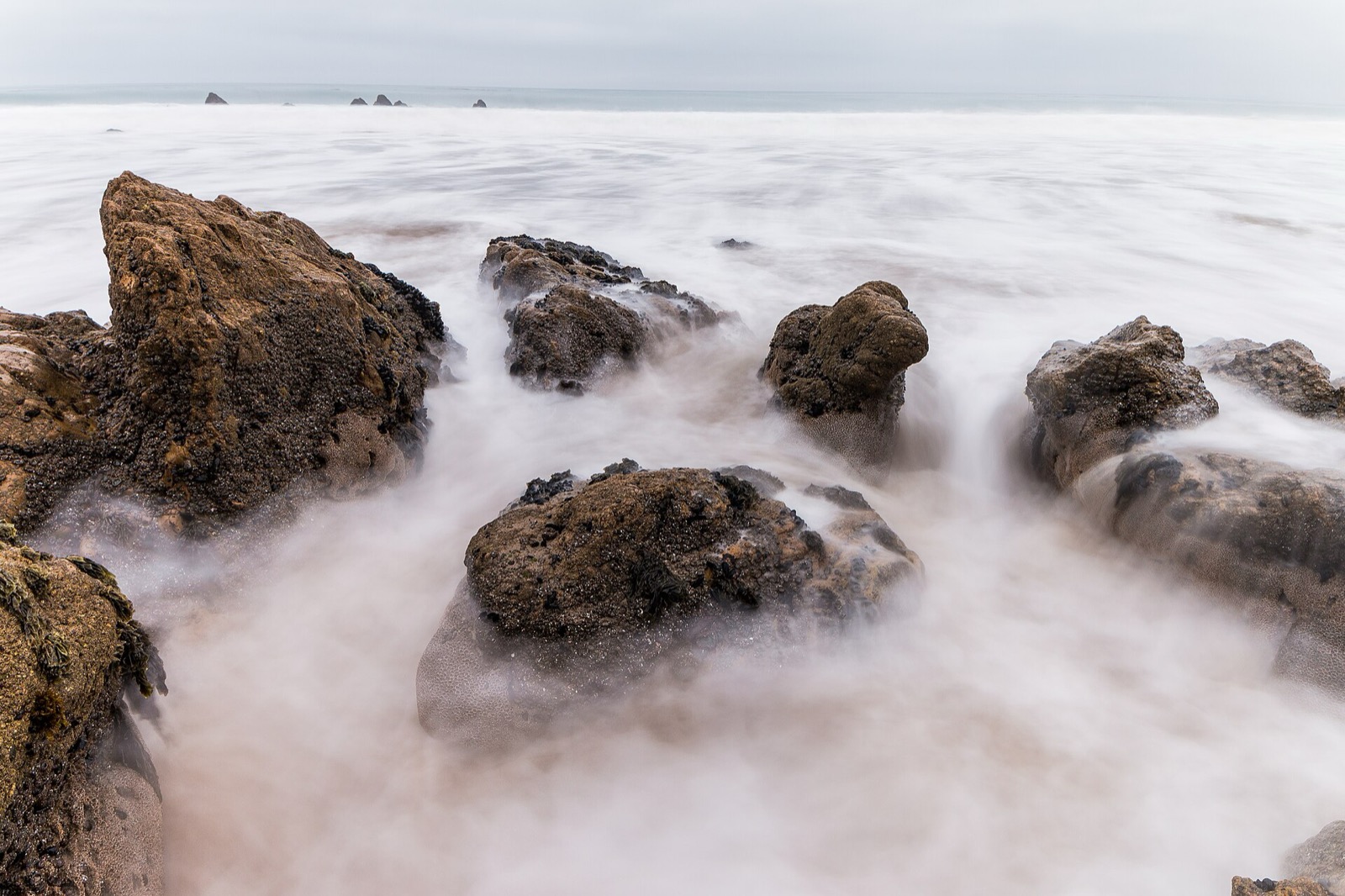 Long exposure of surf washing over dark intertidal rocks at El Matador State Beach, California