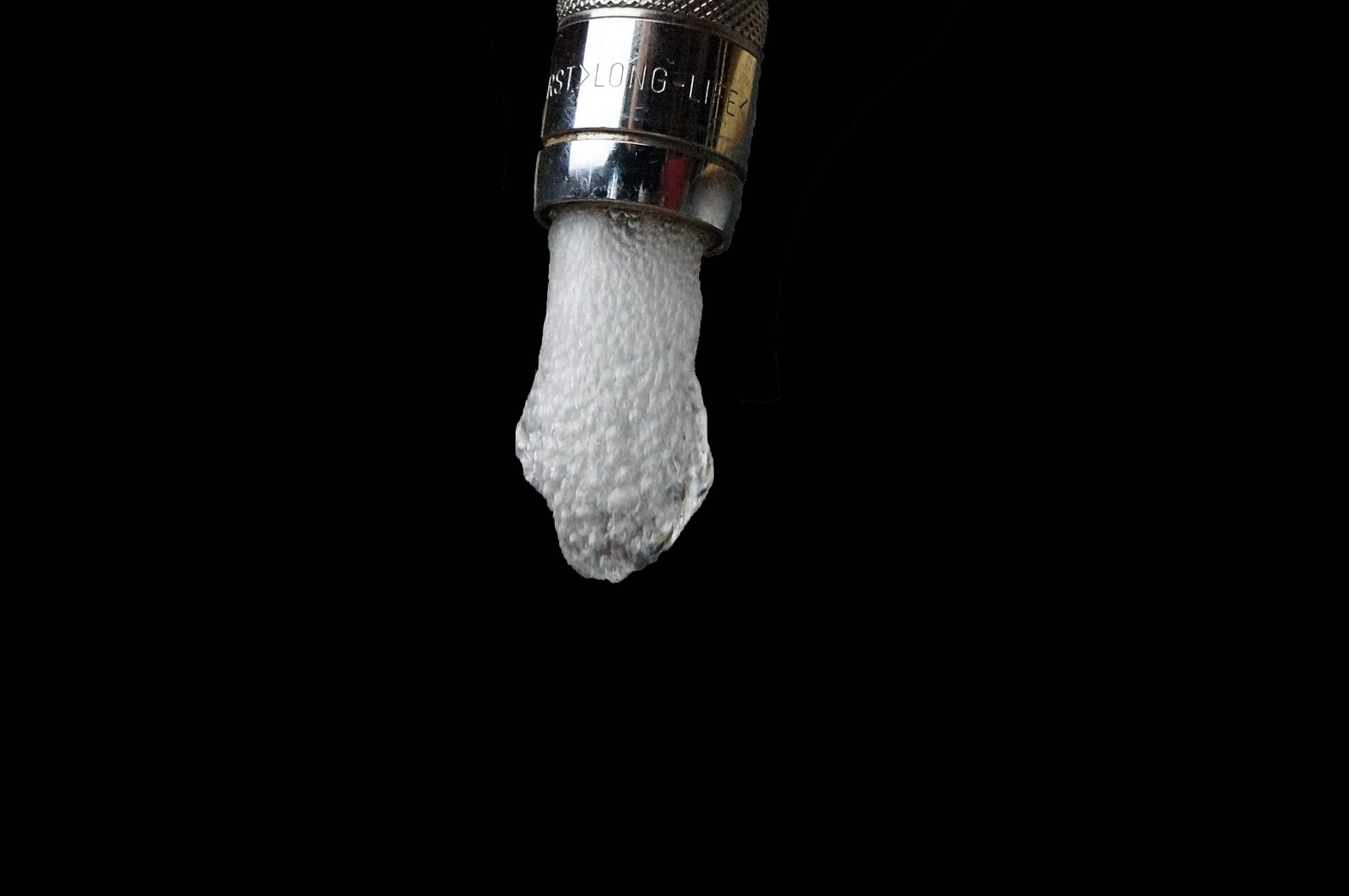 Aerated water flowing from a chrome kitchen faucet against a dark background