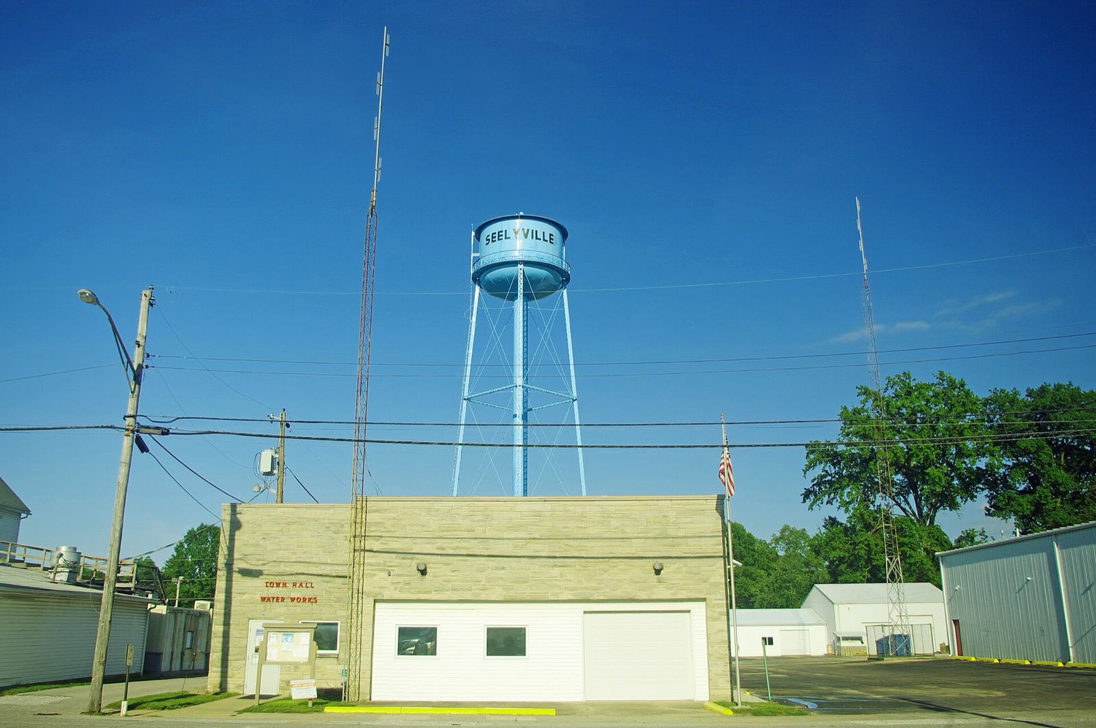 A small town water tower on steel legs against a clear sky