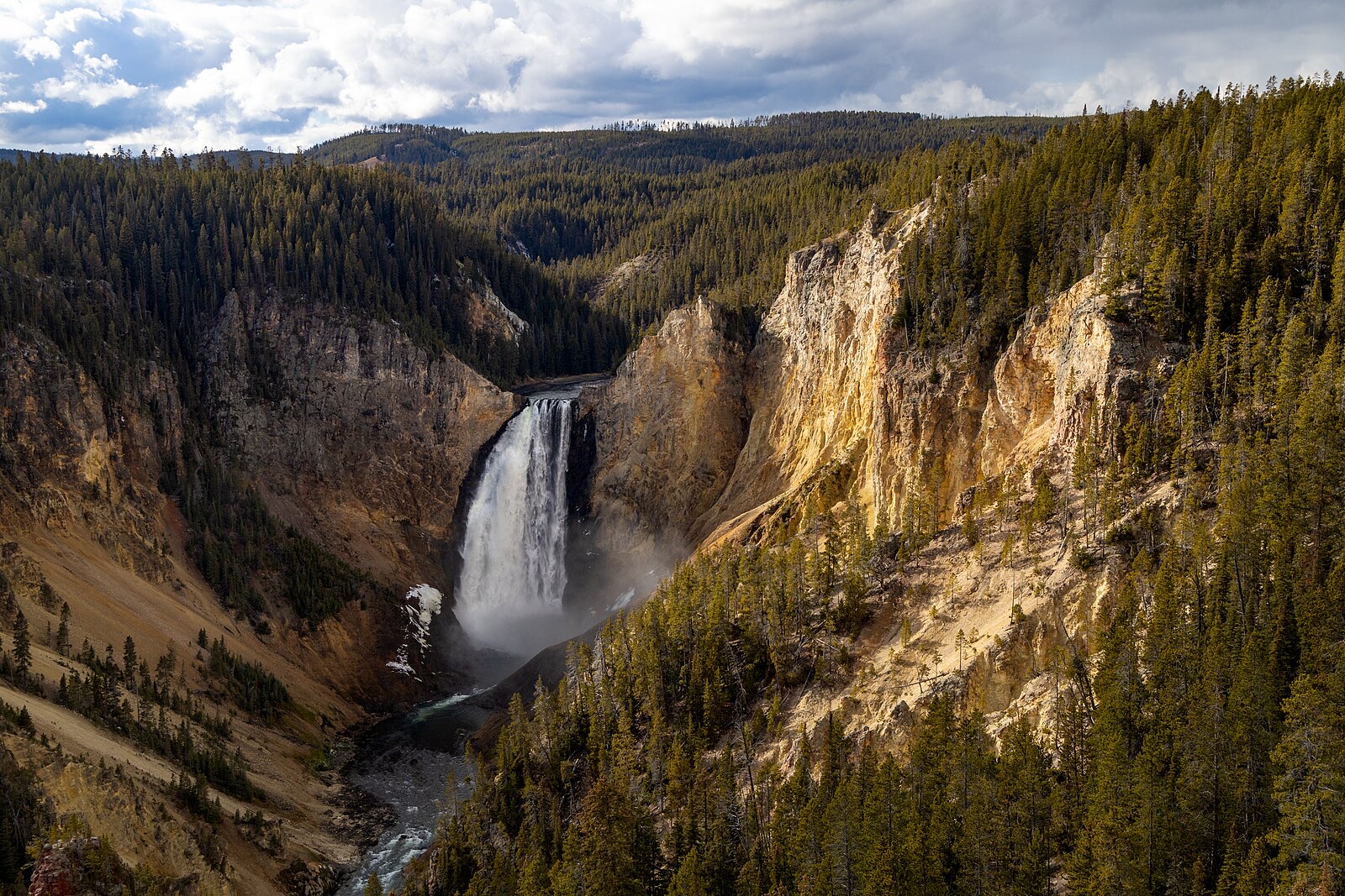 A very tall thin waterfall dropping into a mountain canyon