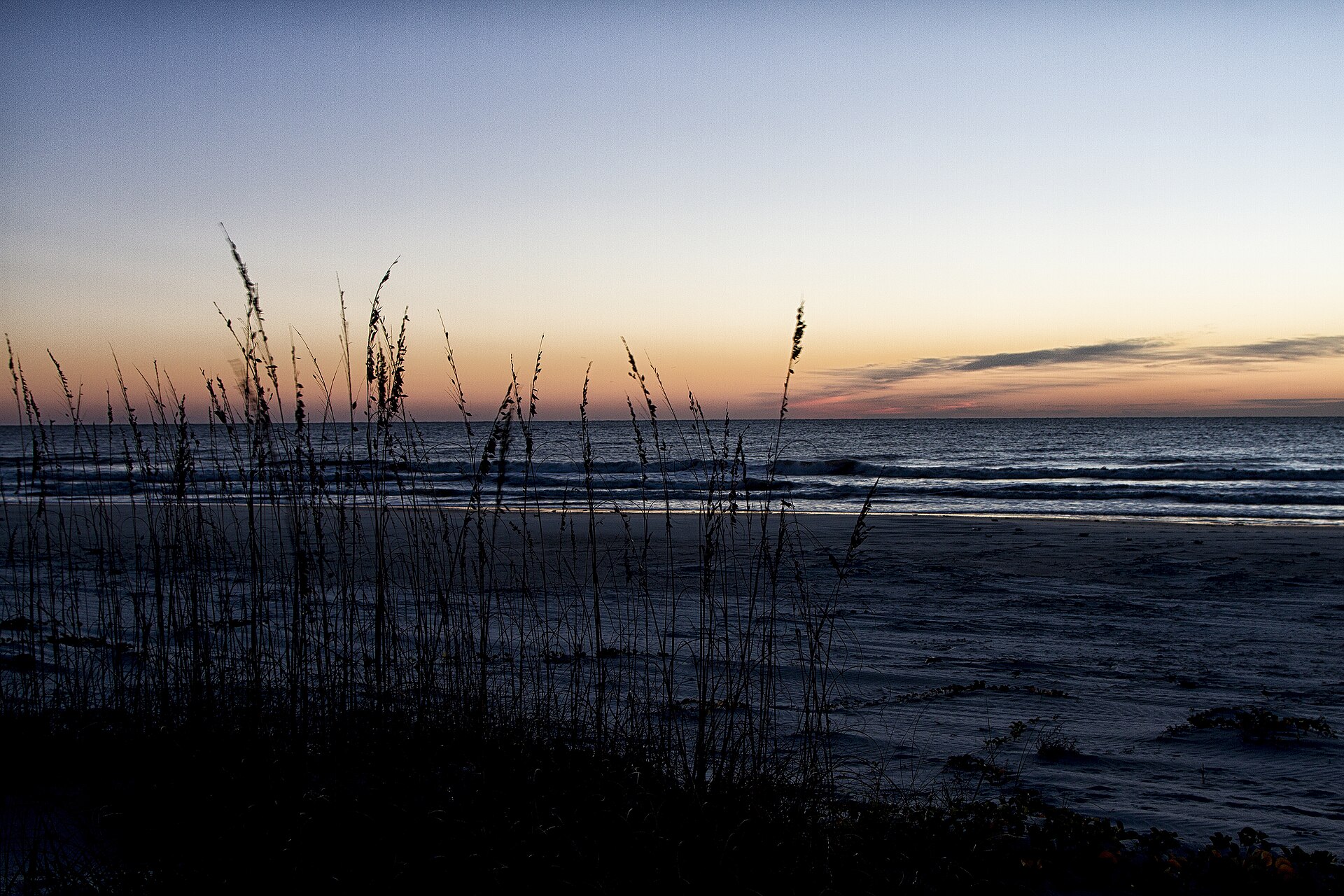 A wide sandy Atlantic beach under an open sky with the sea flat to the horizon